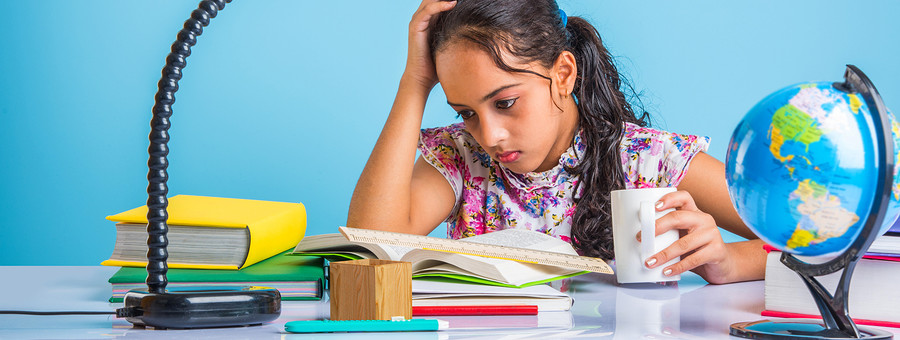 education and home concept - stressed student girl with books, indian girl child tired of studying or doing homework, asian girl studying and stressed, with globe toy and coffee mug
